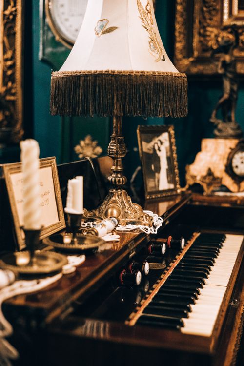 Free A vintage piano with an ornate lamp surrounded by antique decor, evoking historical elegance. Stock Photo