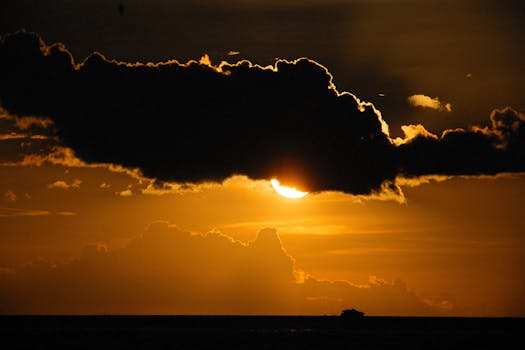 Stunning sunset over the sea with dramatic clouds and silhouetted ship.