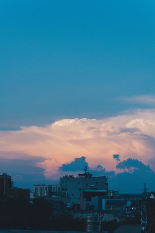 Free City skyline during sunset with vibrant clouds and a blue sky background. Stock Photo