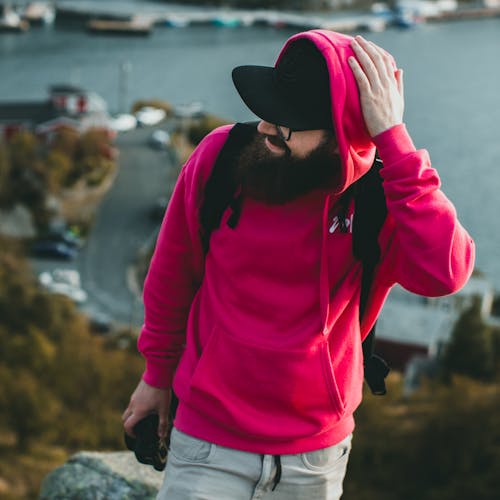 Selective Focus Photo of a Man in a Pink Hoodie Posing with His Hand on His Head