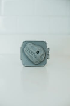 Gray plastic egg mold featuring a dinosaur skull design, perfect for themed culinary creations.