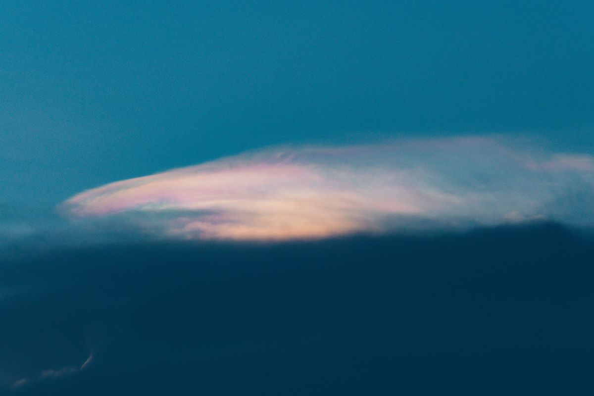 Iridescent cloud at twilight, soft pastel pinks and lavenders bleeding into blue