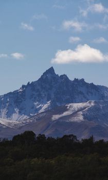 Scenic view of a snow-capped mountain peak under a clear blue sky with greenery in the foreground.