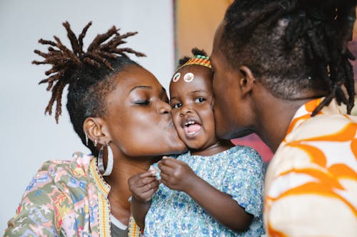 Free A Couple Kissing Their Cute Daughter Stock Photo