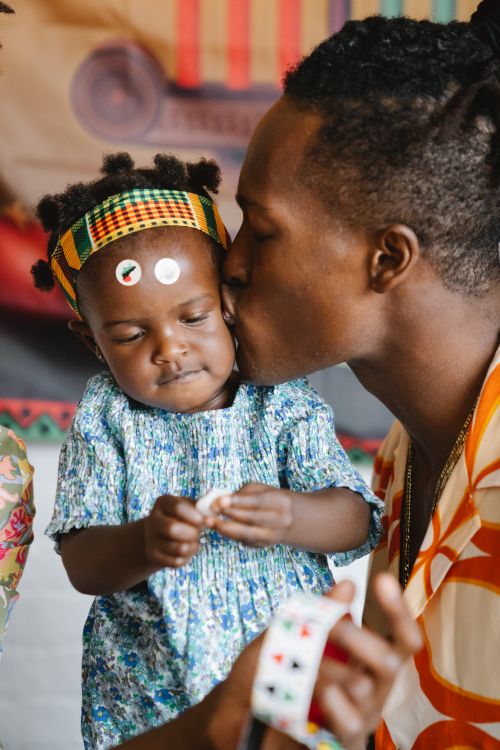 Free A touching moment of a dad kissing his daughter's cheek, showing love and togetherness. Stock Photo