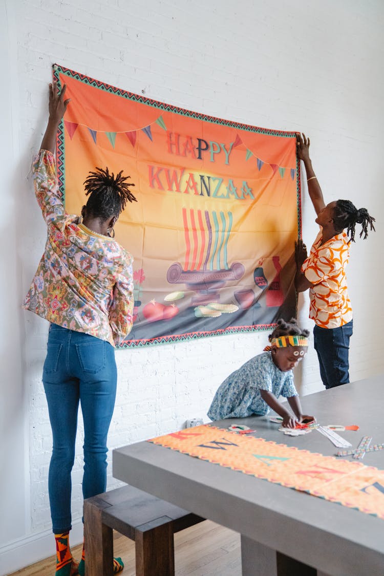 Family Posting A Happy Kwanzaa Banner On A White Wall