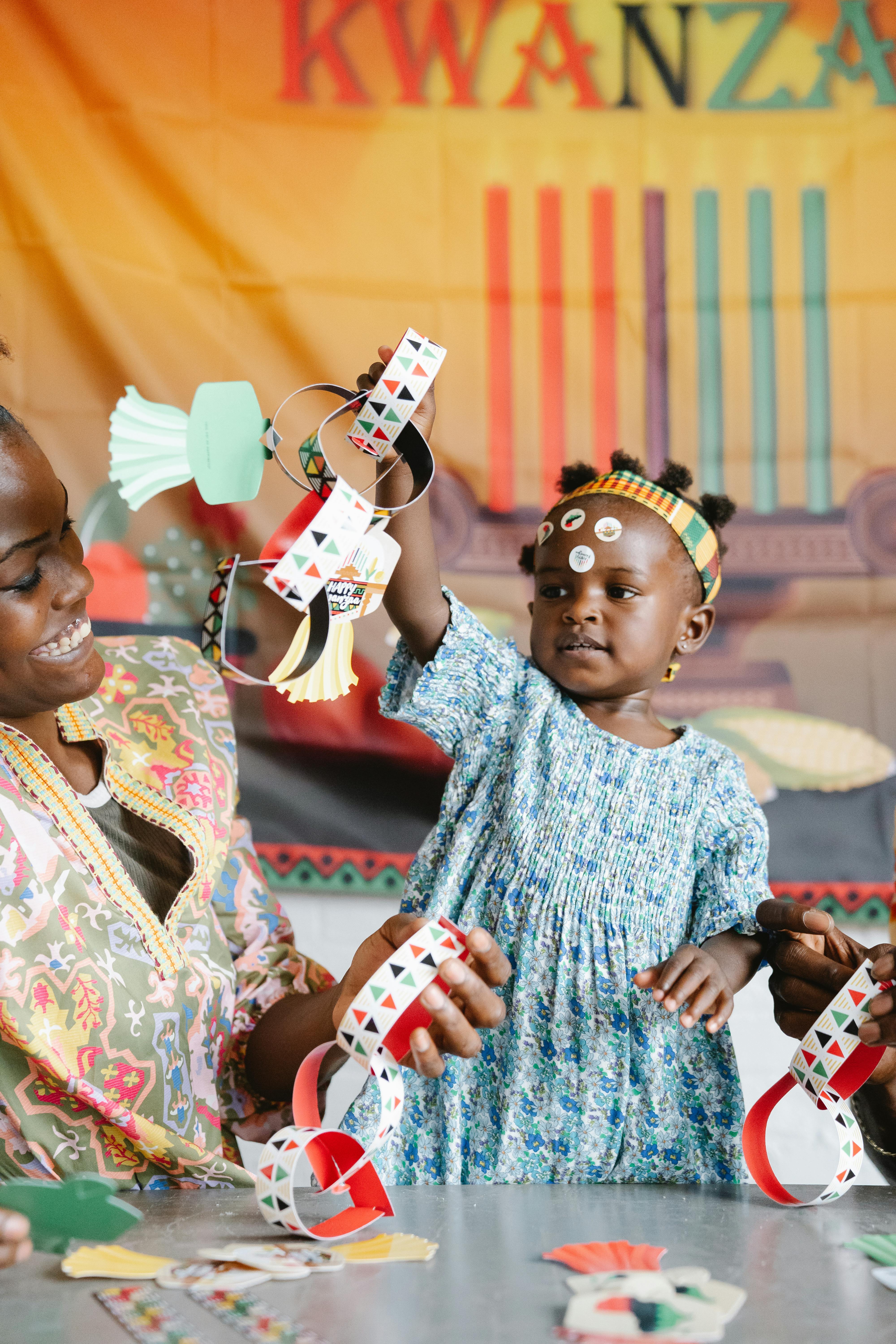 Mother and daughter enjoying Kwanzaa arts and crafts with colorful decorations.