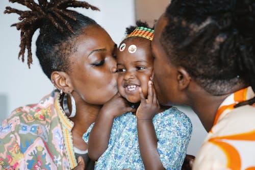 A Couple Kissing Their Cute Daughter