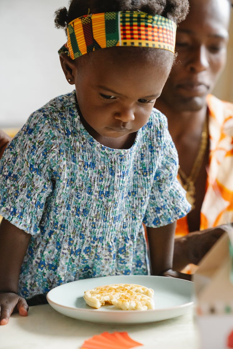 Baby Girl In Blue Dress Eating Breakfast