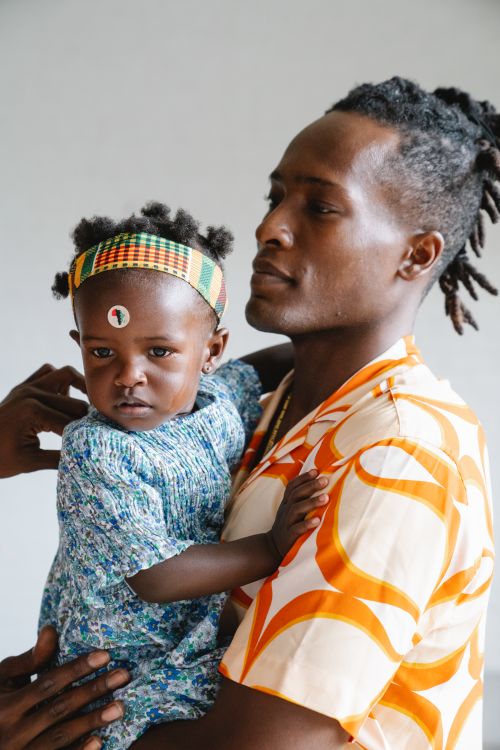 Free A father lovingly holding his daughter in colorful clothing, highlighting cultural fashion. Stock Photo