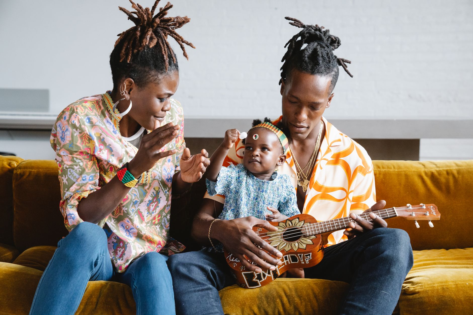A joyful family moment with parents and child enjoying music and laughter.