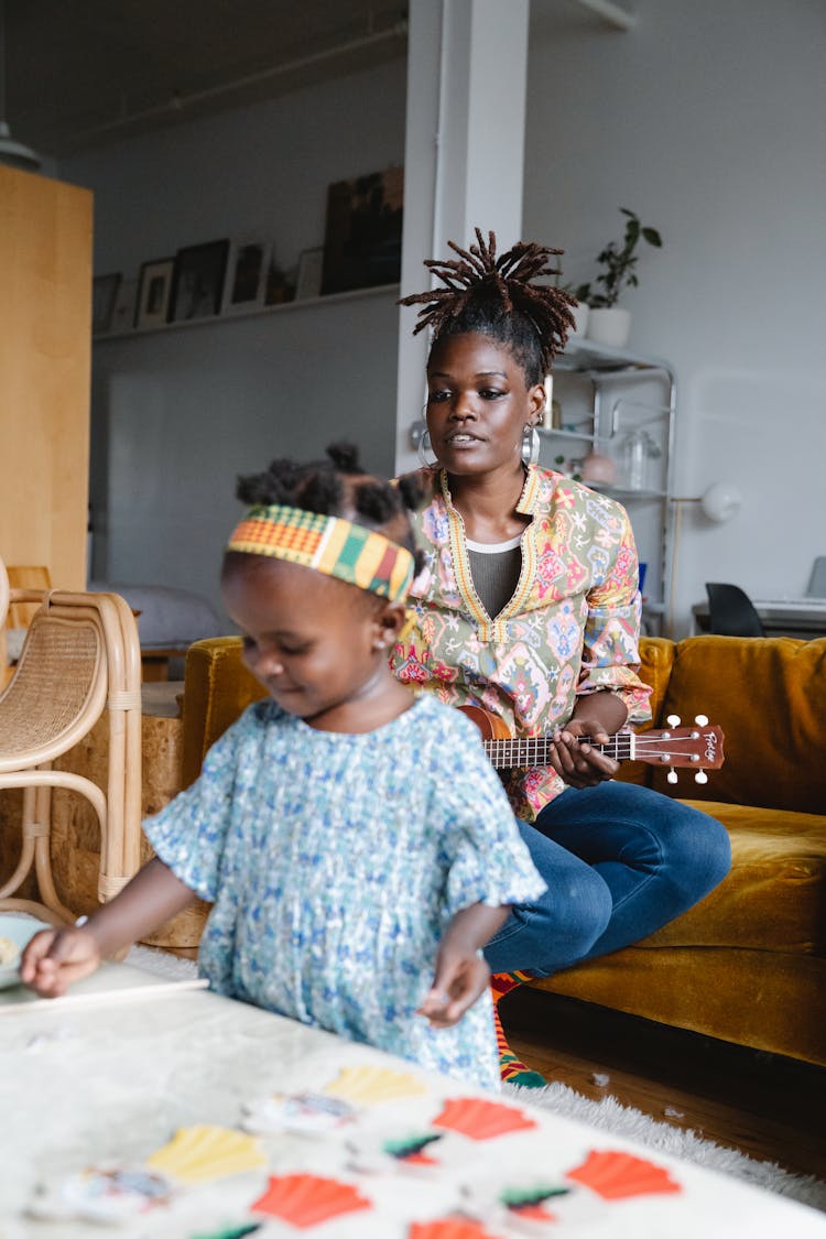 A Mother Playing Ukulele While Singing To Her Daughter