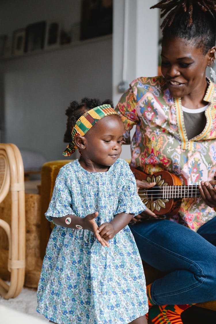 A Mother Playing Ukulele While Singing To Her Daughter