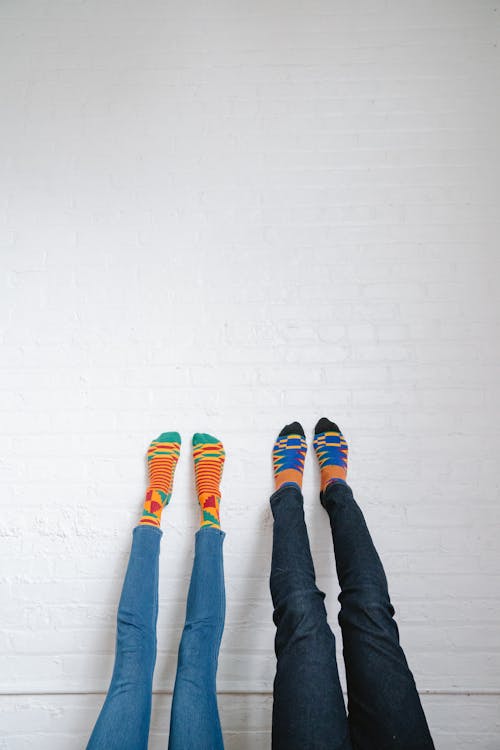 Legs of Two People Touching the White Wall
