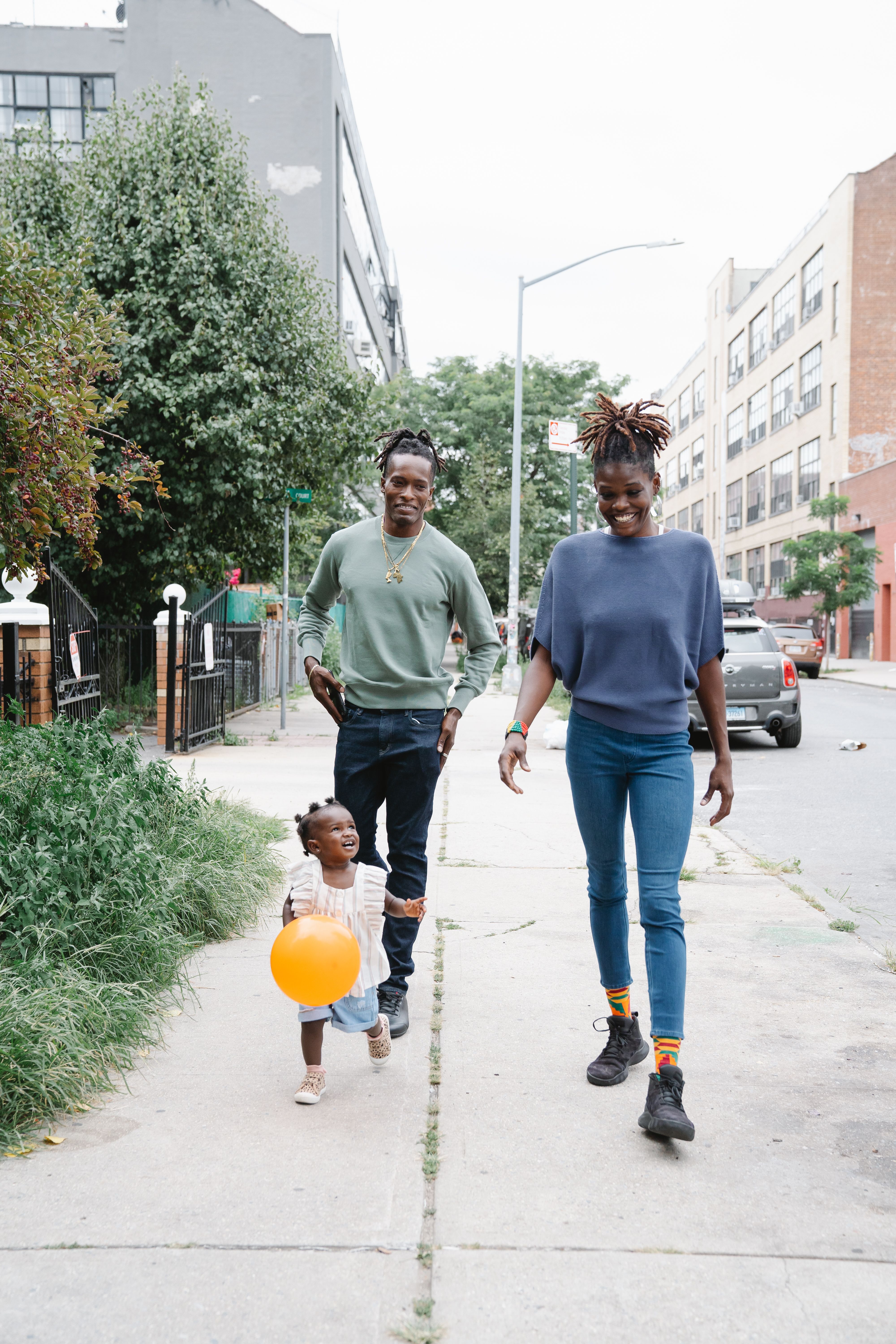 Smiling family taking a stroll with their child in an urban setting.