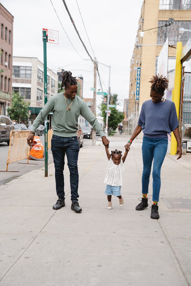 A Happy Family Walking On The Sidewalk