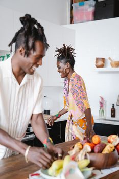 Happy couple laughing together while preparing food in a modern kitchen setting.