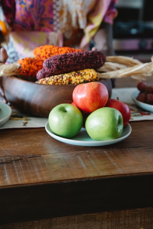 Free A vibrant display of green and red apples on a rustic wooden table with decorative corn. Stock Photo