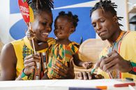 A joyful African family celebrating Kwanzaa with traditional attire and crafts.