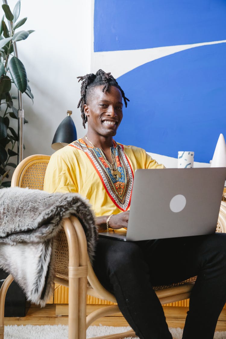 A Man Using His Laptop While Smiling At The Camera