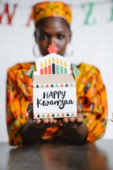 A person holding a Kwanzaa gift box with vibrant colors and traditional patterns.