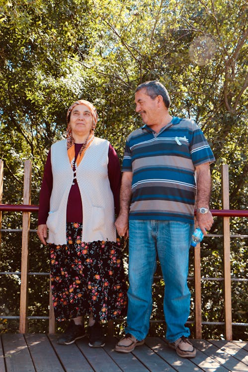 Couple Holding Hands While Standing on Wooden Dock 