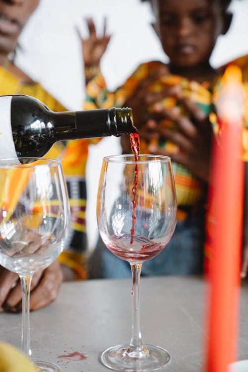 Close-Up Photo of a Person Pouring Red Wine into a Wine Glass