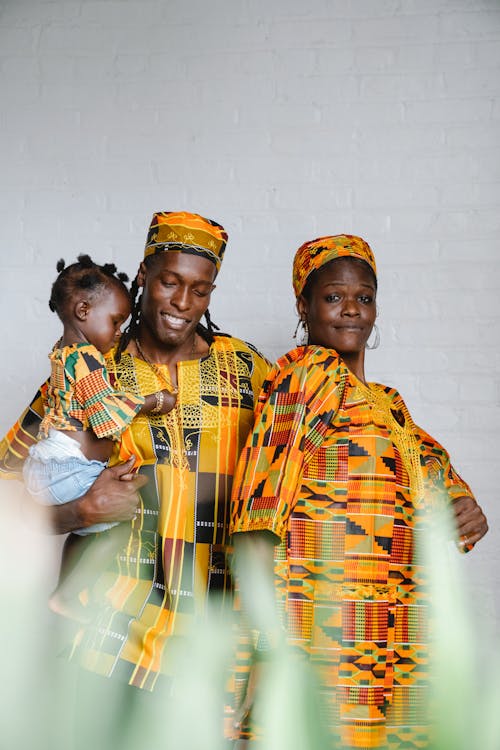 Free Family in Traditional Clothes Standing near the White Wall Stock Photo