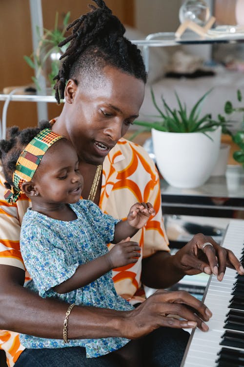 Free Close-Up Shot of a Man and His Daughter Playing Piano Stock Photo