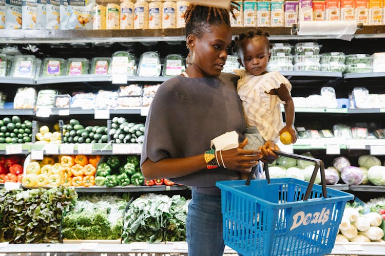 A Mother Carrying Her Daughter And Shopping Basket