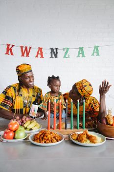 Family celebrating Kwanzaa with traditional attire and festive decorations indoors.