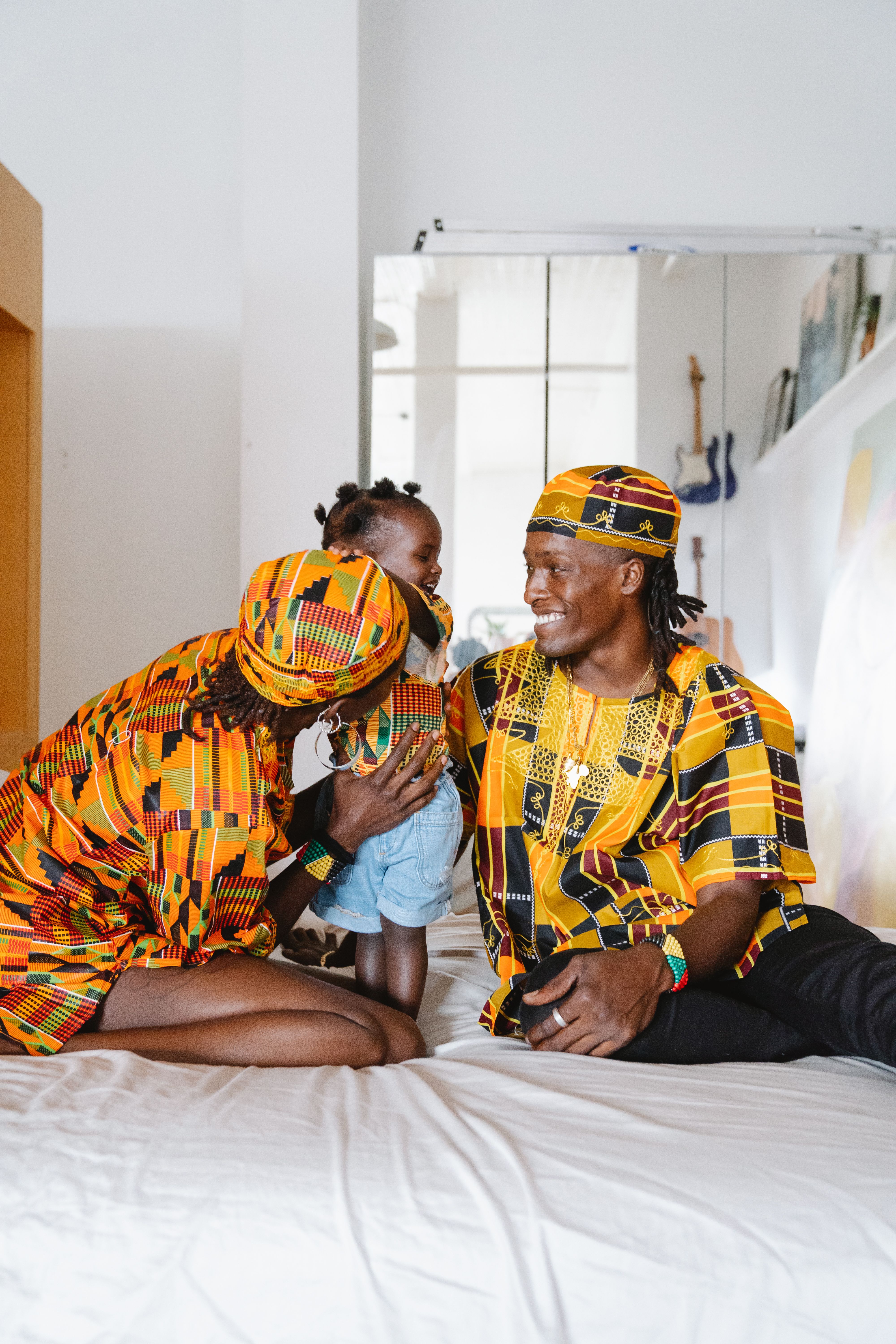 Family of three in vibrant African attire sharing a joyful moment indoors.