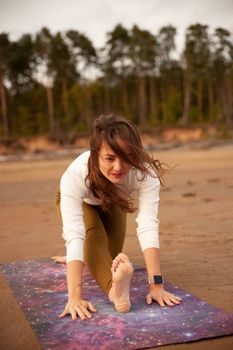 Woman stretches on a yoga mat at the beach, embracing a healthy lifestyle.
