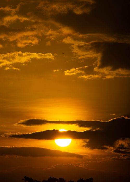 Free Breathtaking sunset with vibrant clouds and silhouetted horizon. Stock Photo