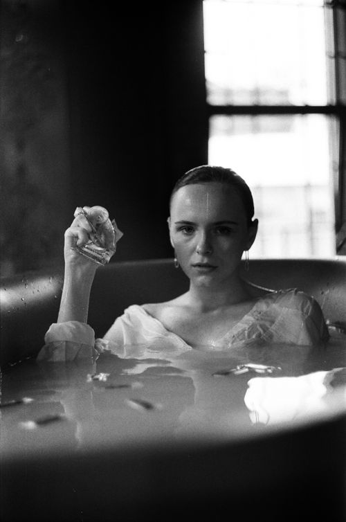 Free Black and white photo of a woman in a bathtub, holding a glass, creating a serene atmosphere. Stock Photo