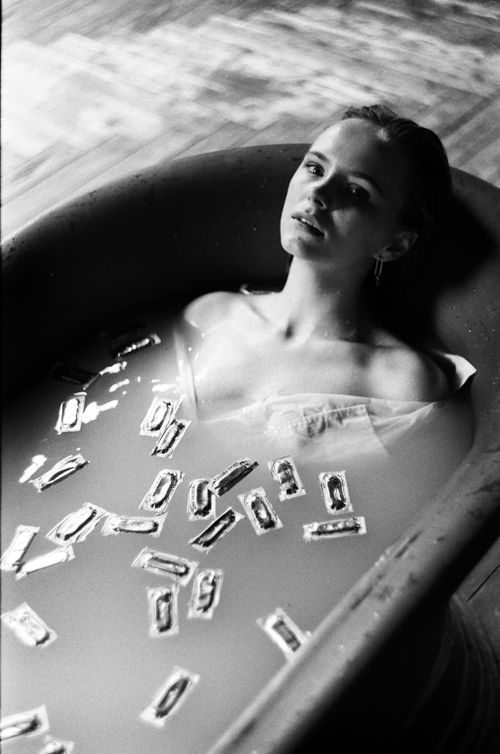 Free Elegant monochrome image of a woman in a bathtub with floating packets, evoking a sense of mystery. Stock Photo