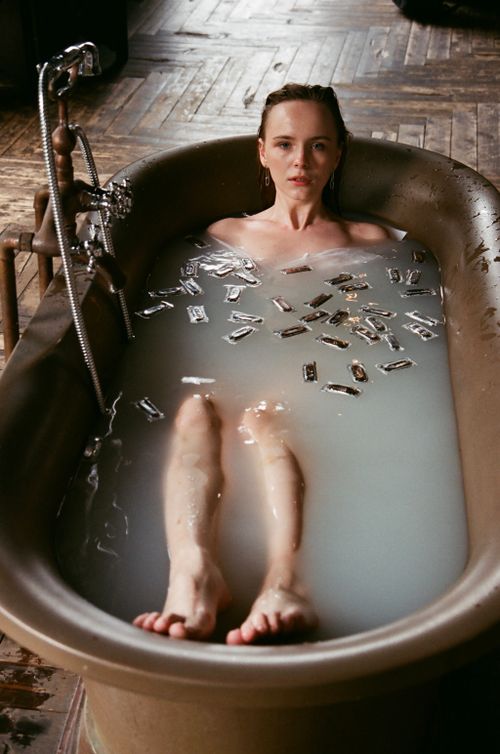 Free Caucasian woman enjoying a soothing bath in a vintage tub surrounded by milk and sachets. Stock Photo
