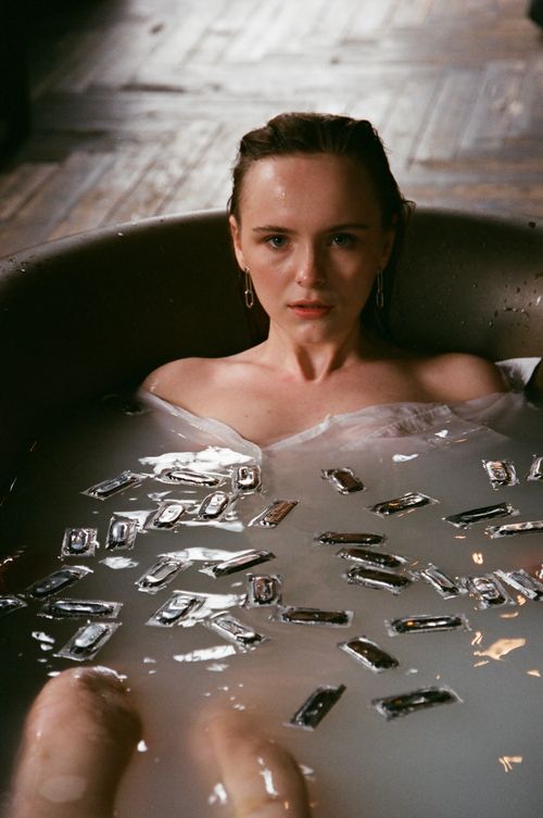 Free Caucasian woman taking a therapeutic milk bath with small packets floating around for relaxation. Stock Photo