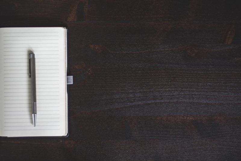 Notebook and pen on a dark desk — Negative Space on Pexels