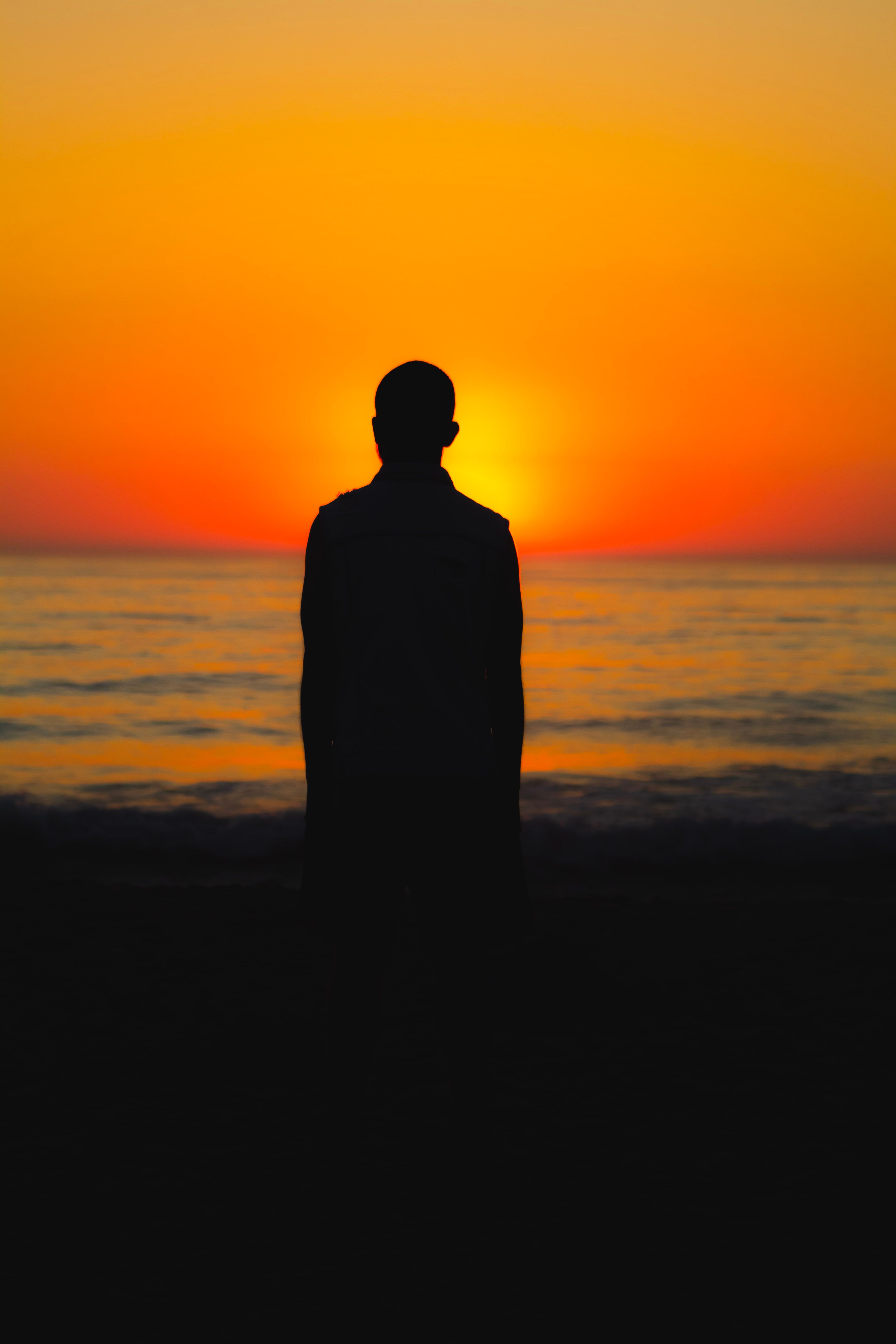 Silhouette of Man Standing on Seashore during Sunset · Free Stock Photo