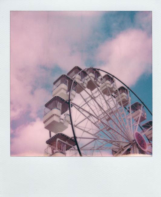 Polaroid of a Ferris wheel set against dreamy pink and blue skies.