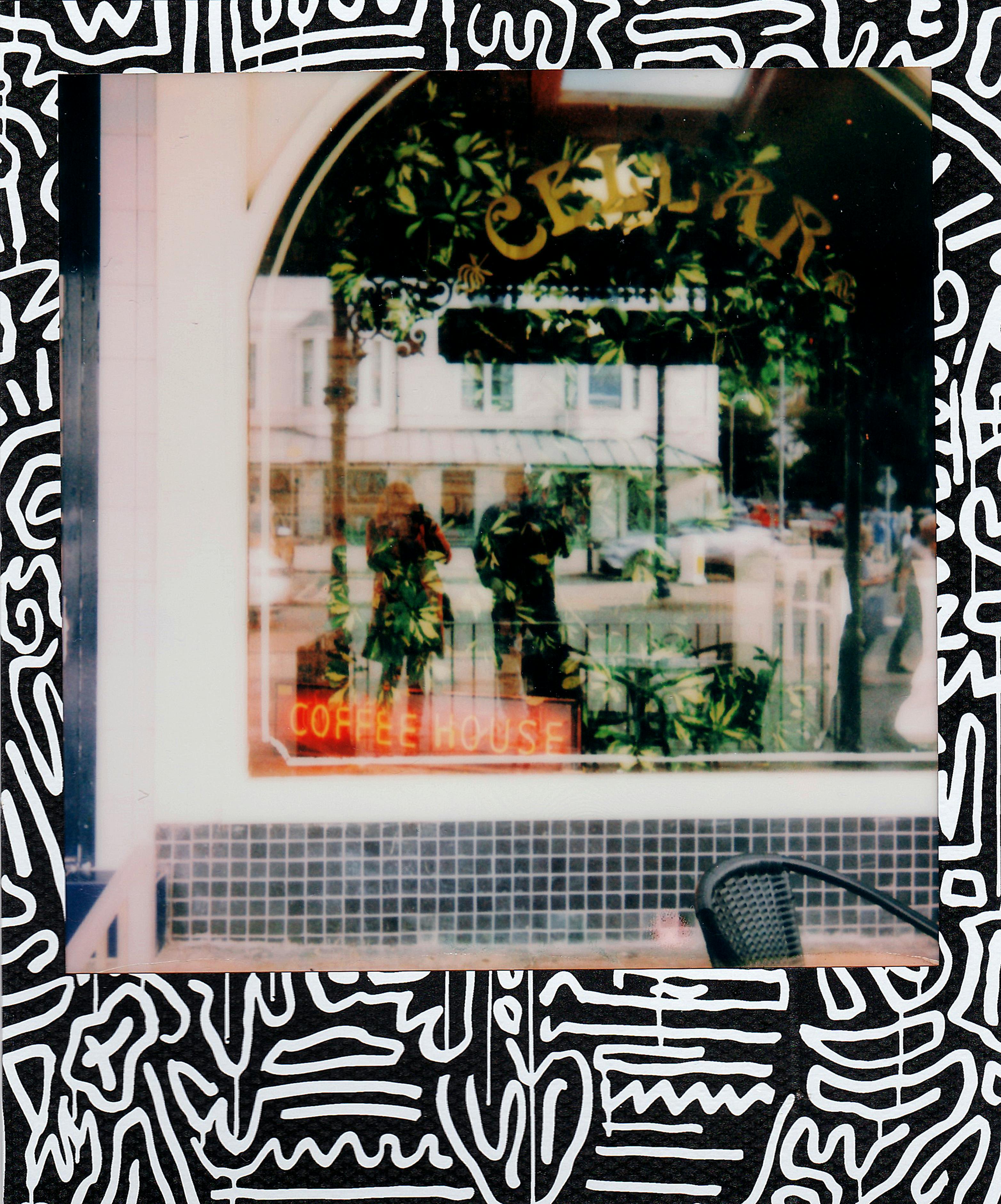Artistic reflection in a coffee shop window with abstract black and white border design.