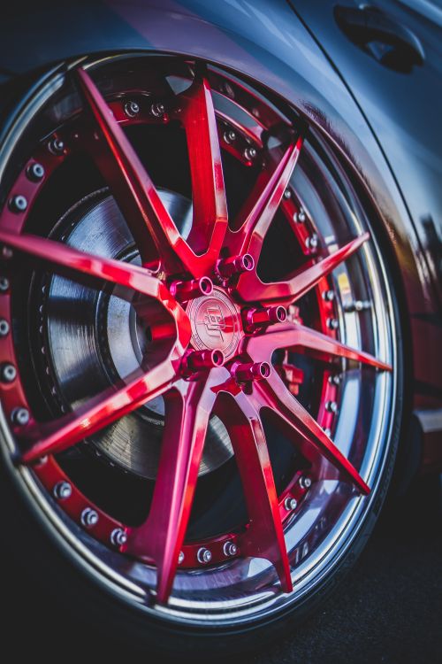 Free Close-up of a vibrant red custom car wheel with intricate design and polished rim. Stock Photo