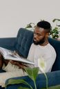 Bearded Man Sitting on Blue Sofa while Reading a Magazine