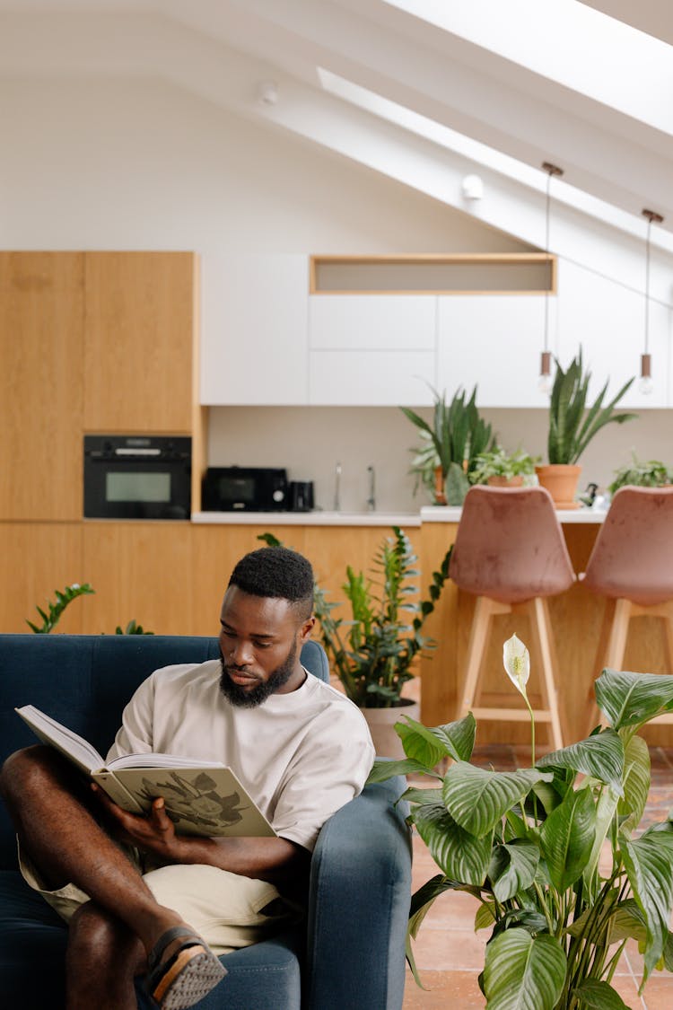 Person Sitting On Sofa While Reading A Magazine