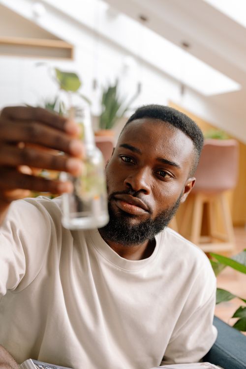 Free An adult man in a white shirt, analyzing the contents of a clear bottle indoors. Stock Photo