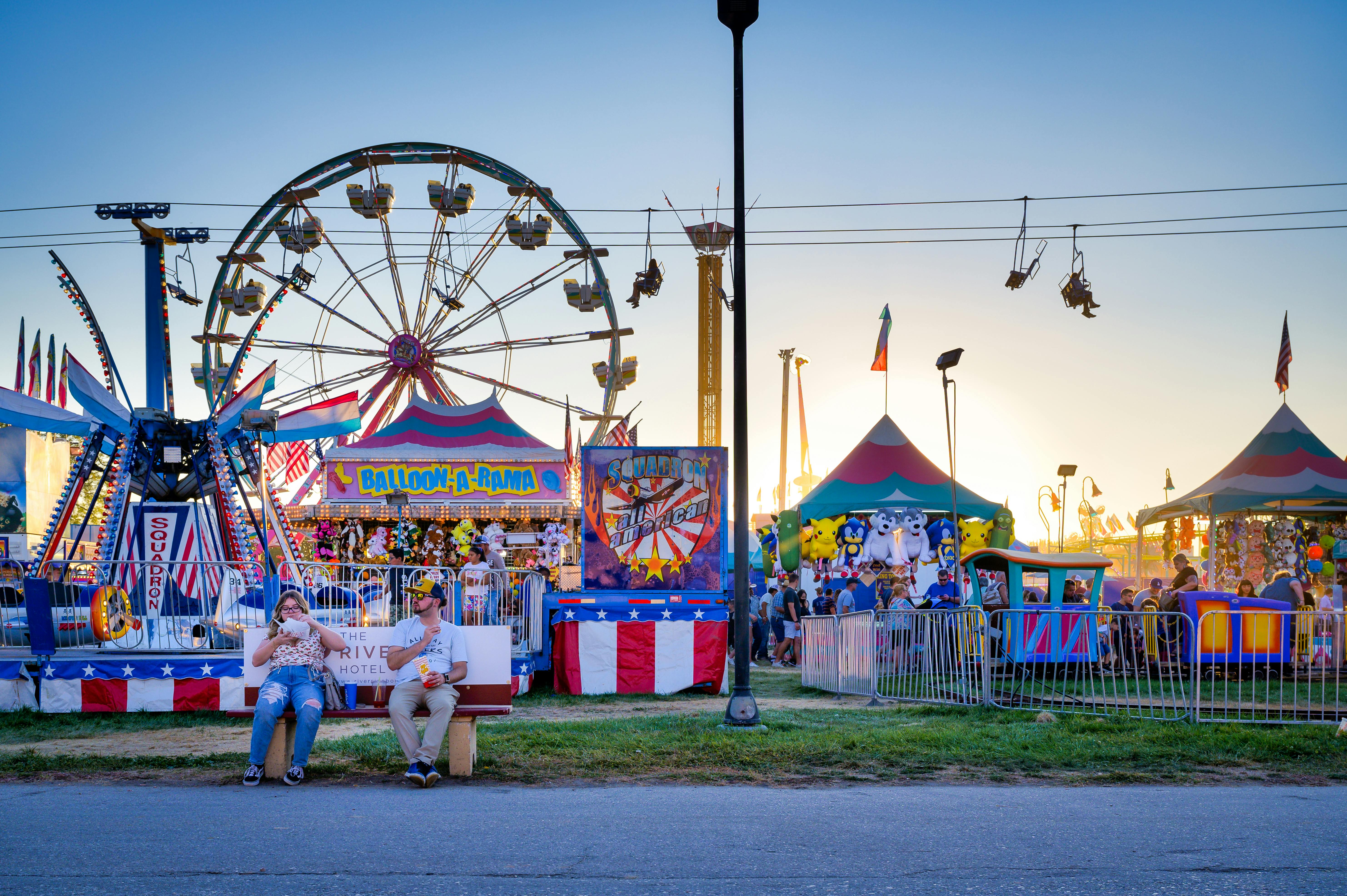 A lively amusement park scene in Boise, featuring a Ferris wheel and various rides at sunset.