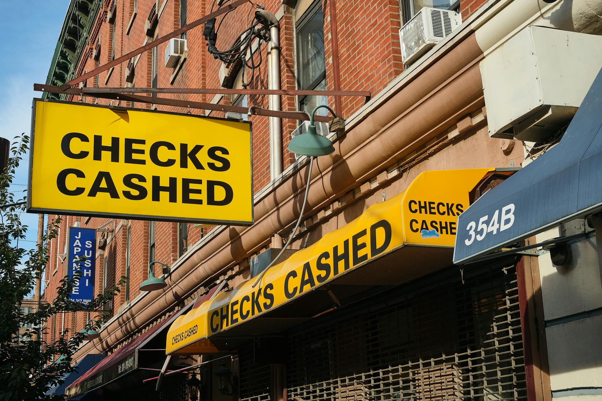 Close-up of a Checks Cashed storefront signage on a street in Jersey City, NJ.