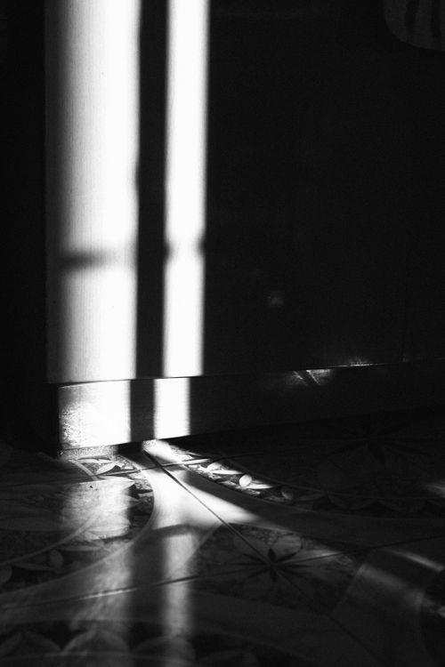 Free Black and white image of a shadow cast on a decorative tiled floor, creating a dramatic contrast. Stock Photo