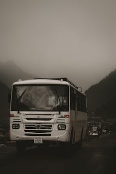 A bus travels on a foggy mountain road, creating a mysterious and moody scene.